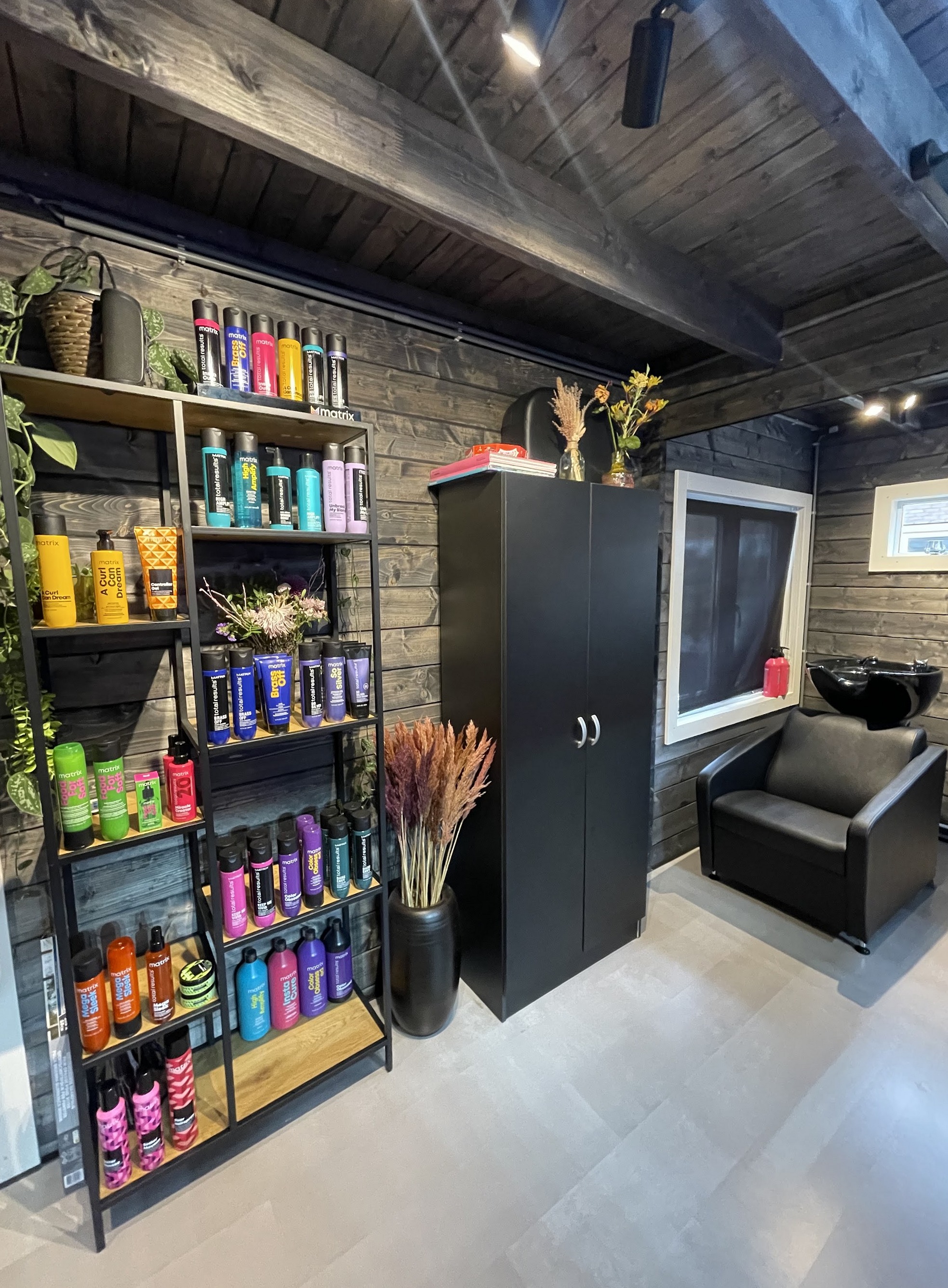 Het productenrek, de zwarte kast en de wasstoel in de salon