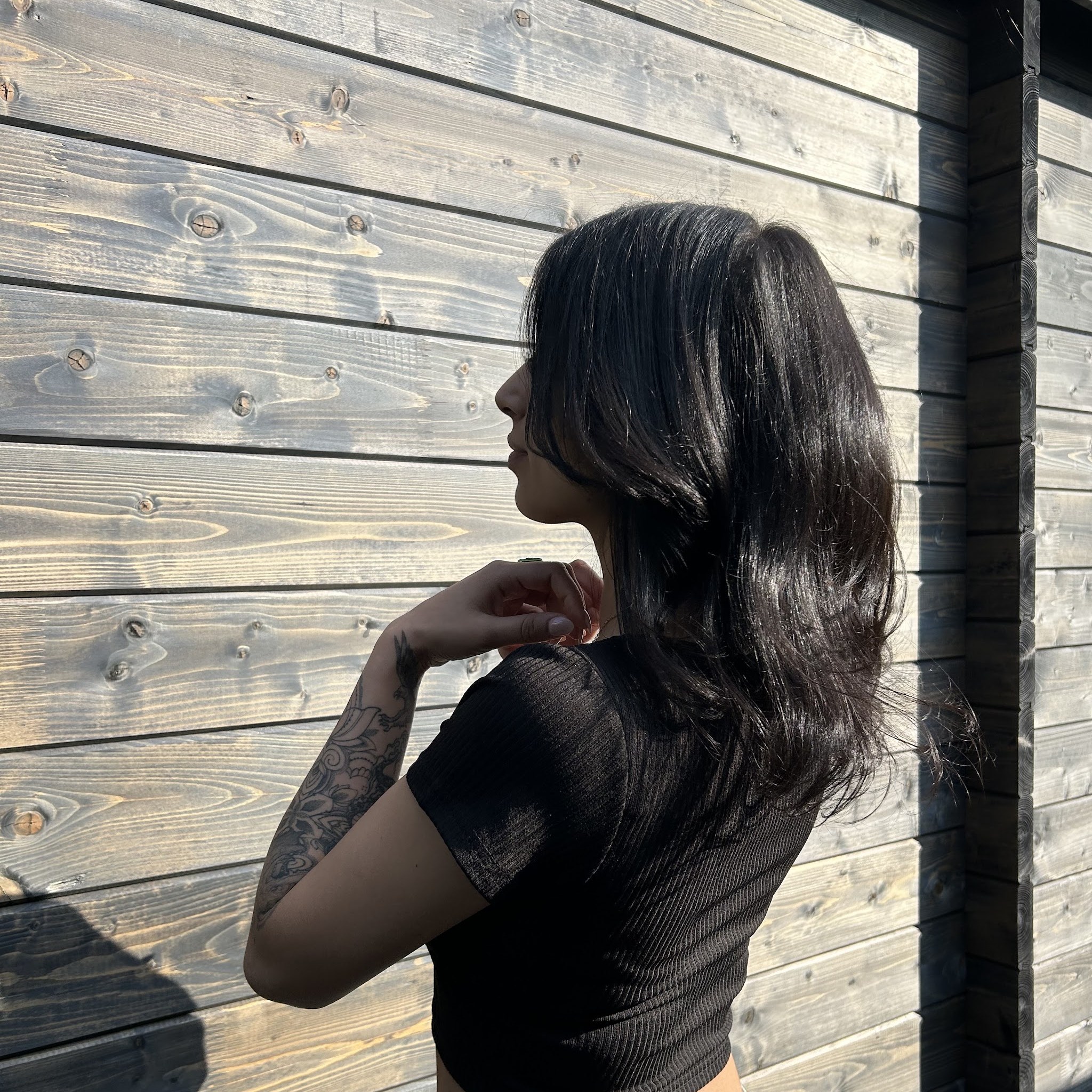 Lang donker haar in laagjes, gefotografeerd tegen de houten wand van de salon